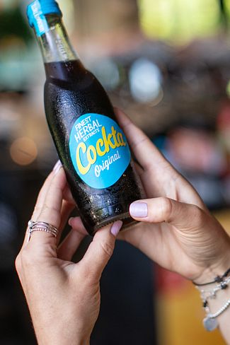 Eine Frau mit einer Cockta Flasche in der Hand