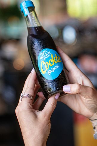 Eine Frau mit einer Cockta Flasche in der Hand