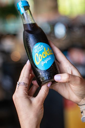 Eine Frau mit einer Cockta Flasche in der Hand