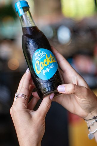 Eine Frau mit einer Cockta Flasche in der Hand
