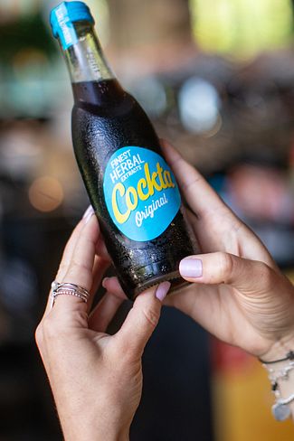 Eine Frau mit einer Cockta Flasche in der Hand